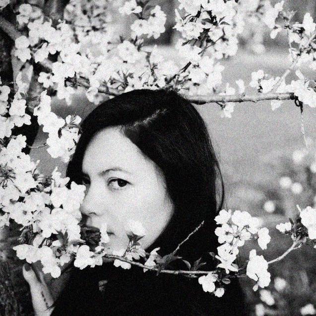 Black-and-white portrait of Mel Tjoeng among blossoms