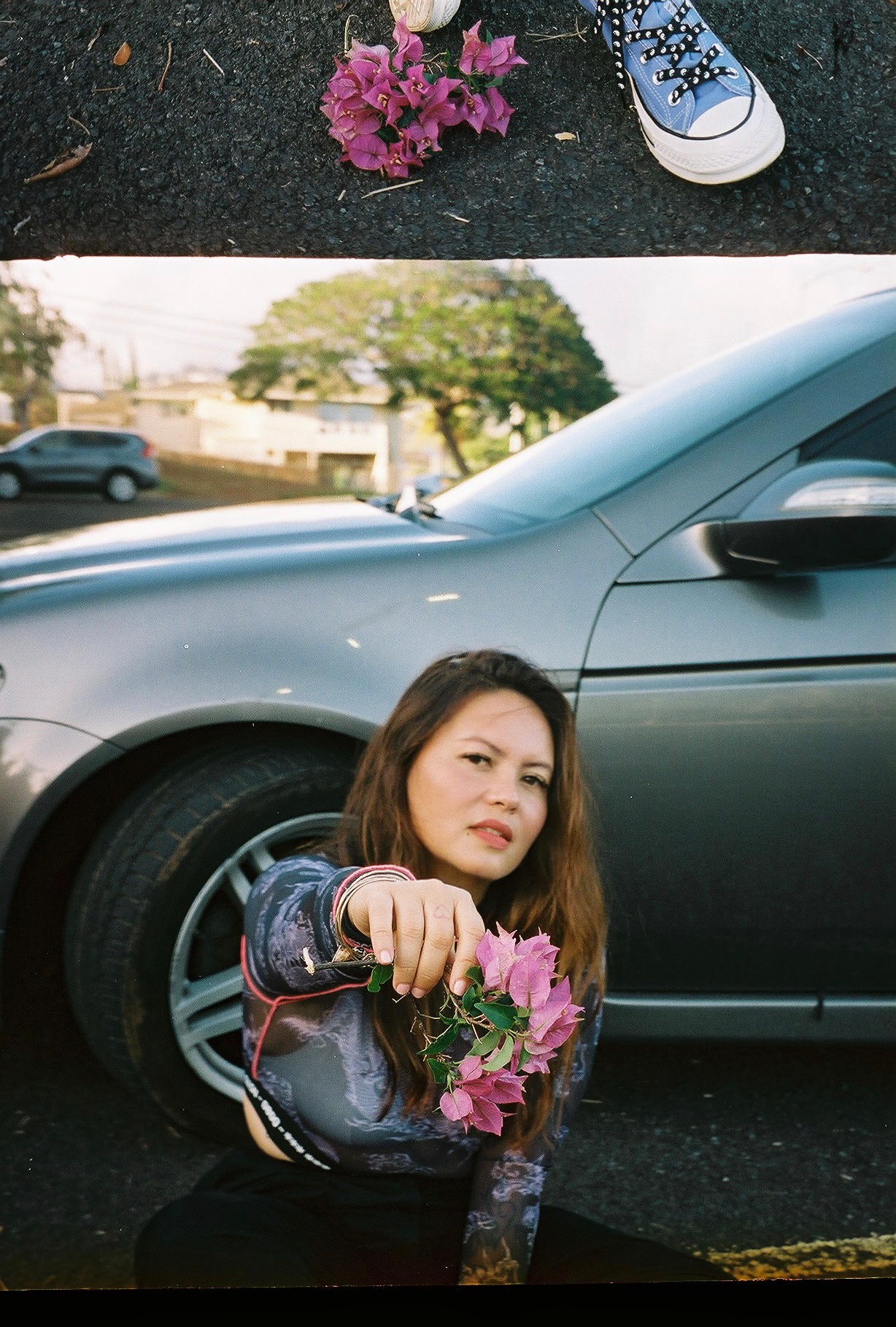 Mel Tjoeng holding pink flowers beside a silver car